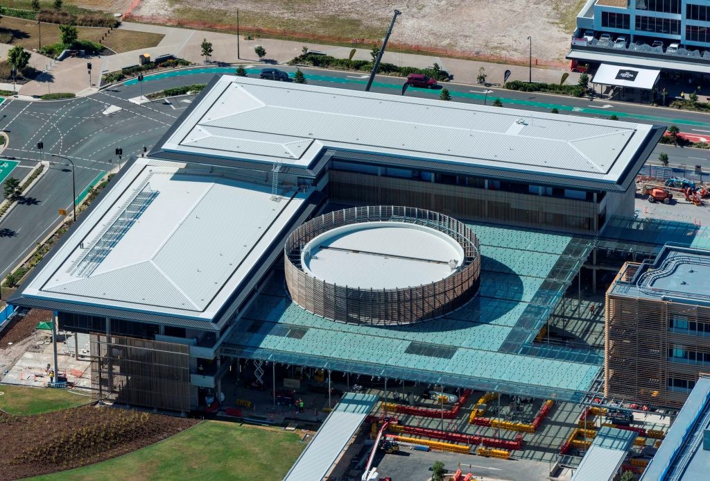 Glass awning covering large outdoor area between adjoining hospital buildings